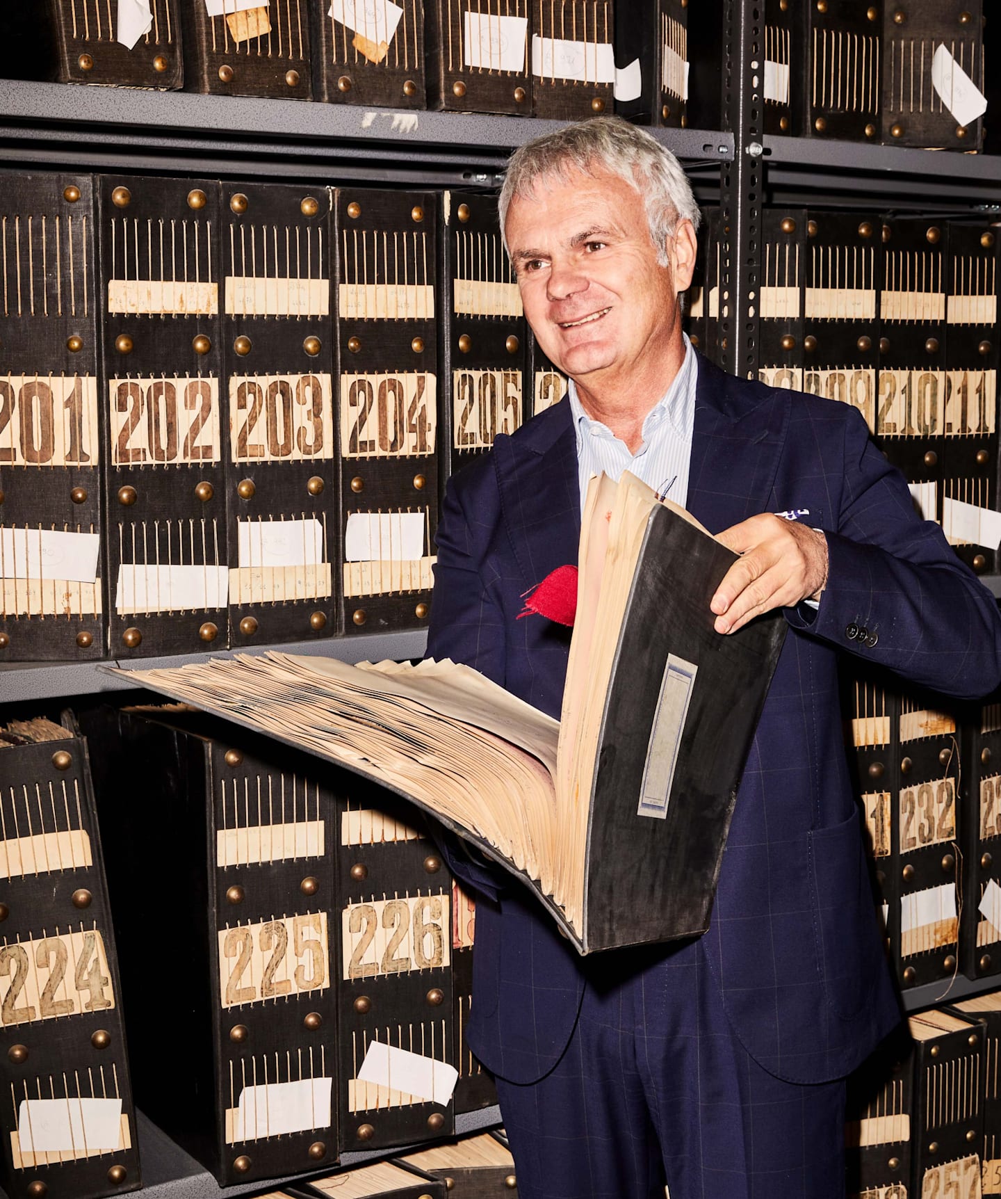 El CEO del telar Tallia di Delfini con un libro de archivo que exhibe los tejidos utilizados desde 1903.