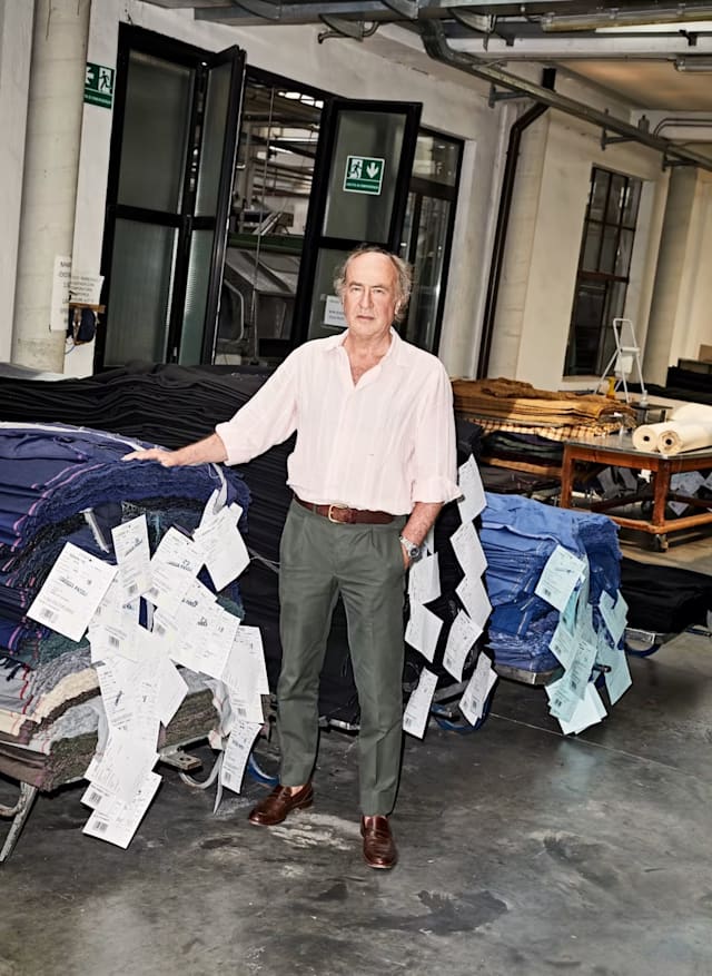 Giorgo Thomas, CEO of E. Thomas mill, standing in factory with fabric rolls