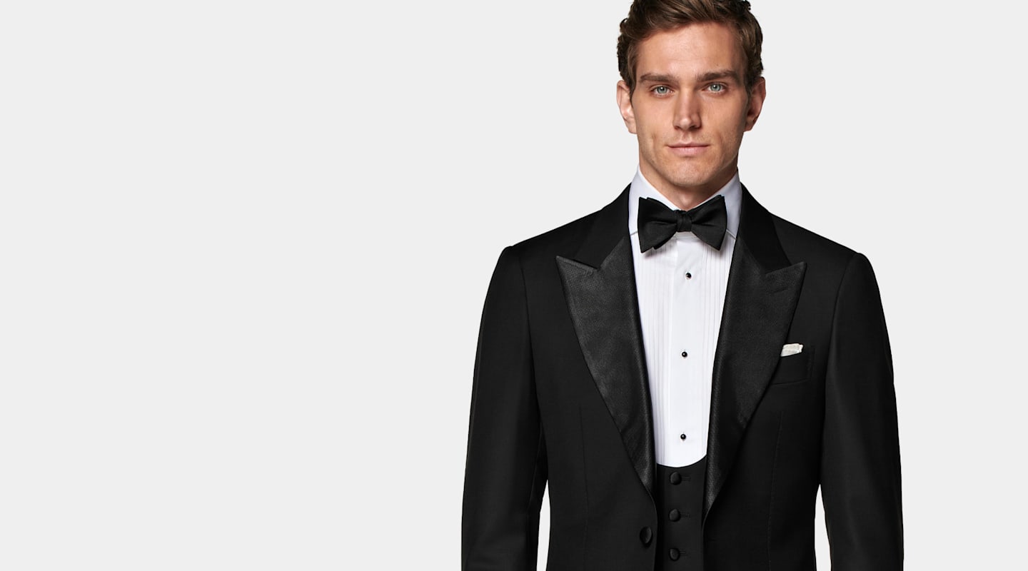 Detail of black tuxedo with pleated white shirt and black silk bow tie.