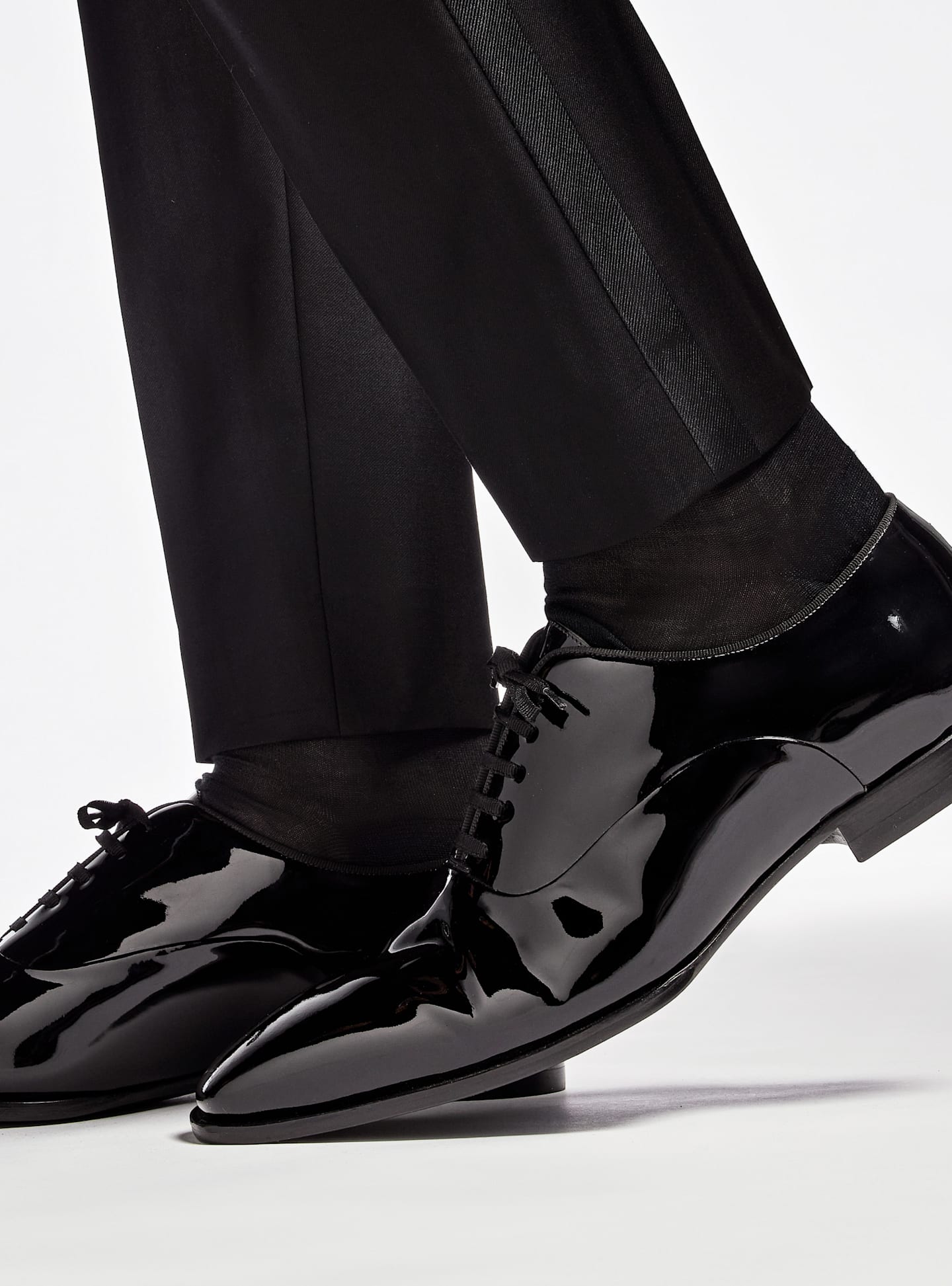 Detail shot of black patent leather tuxedo shoes.