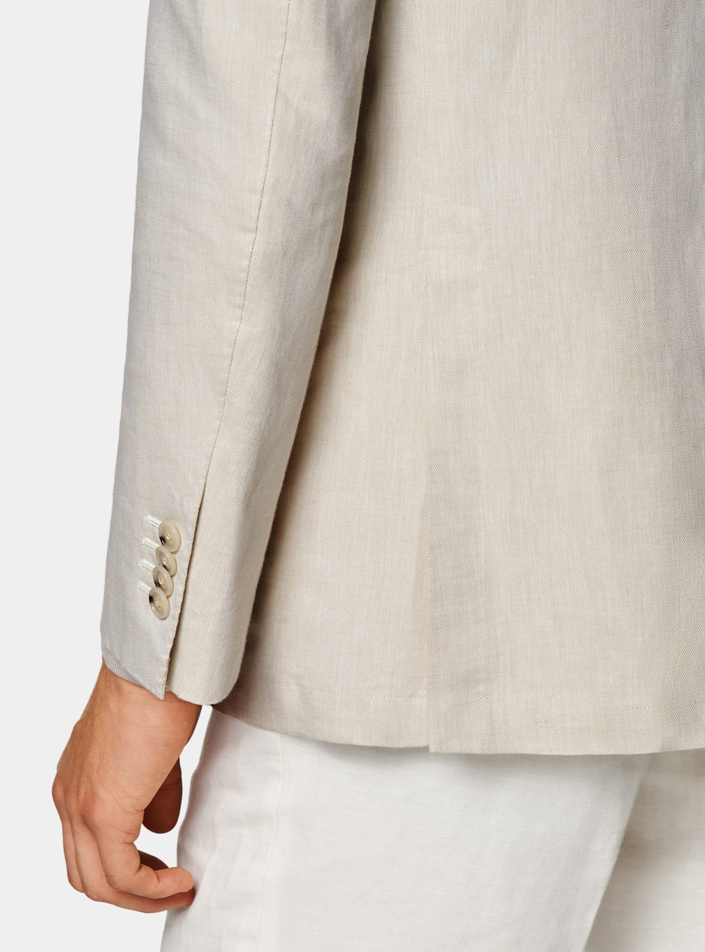 Dettaglio di una giacca marrone chiaro e camicia color taupe.