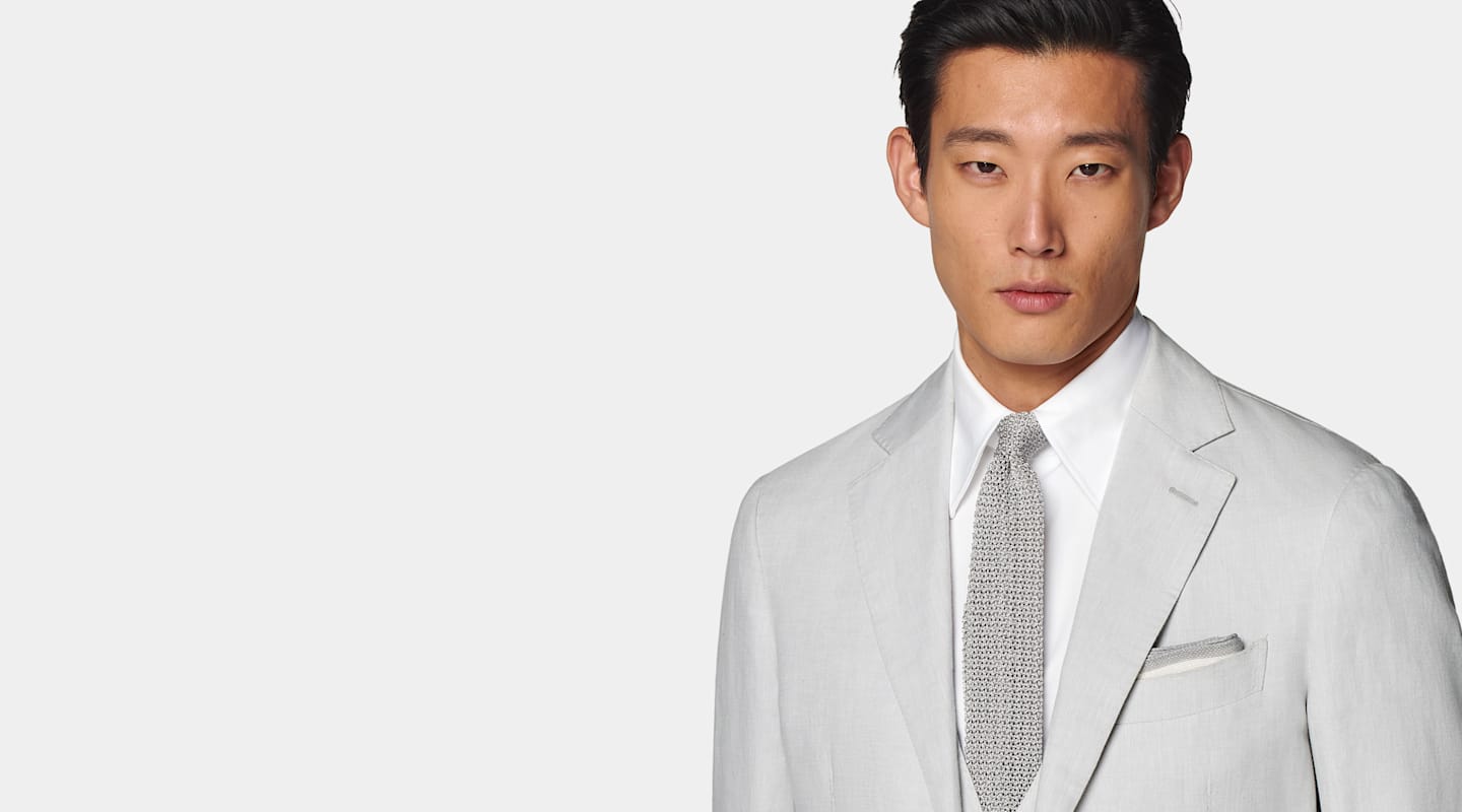 Traje gris con camisa blanca y corbata de punto gris hecha en seda.