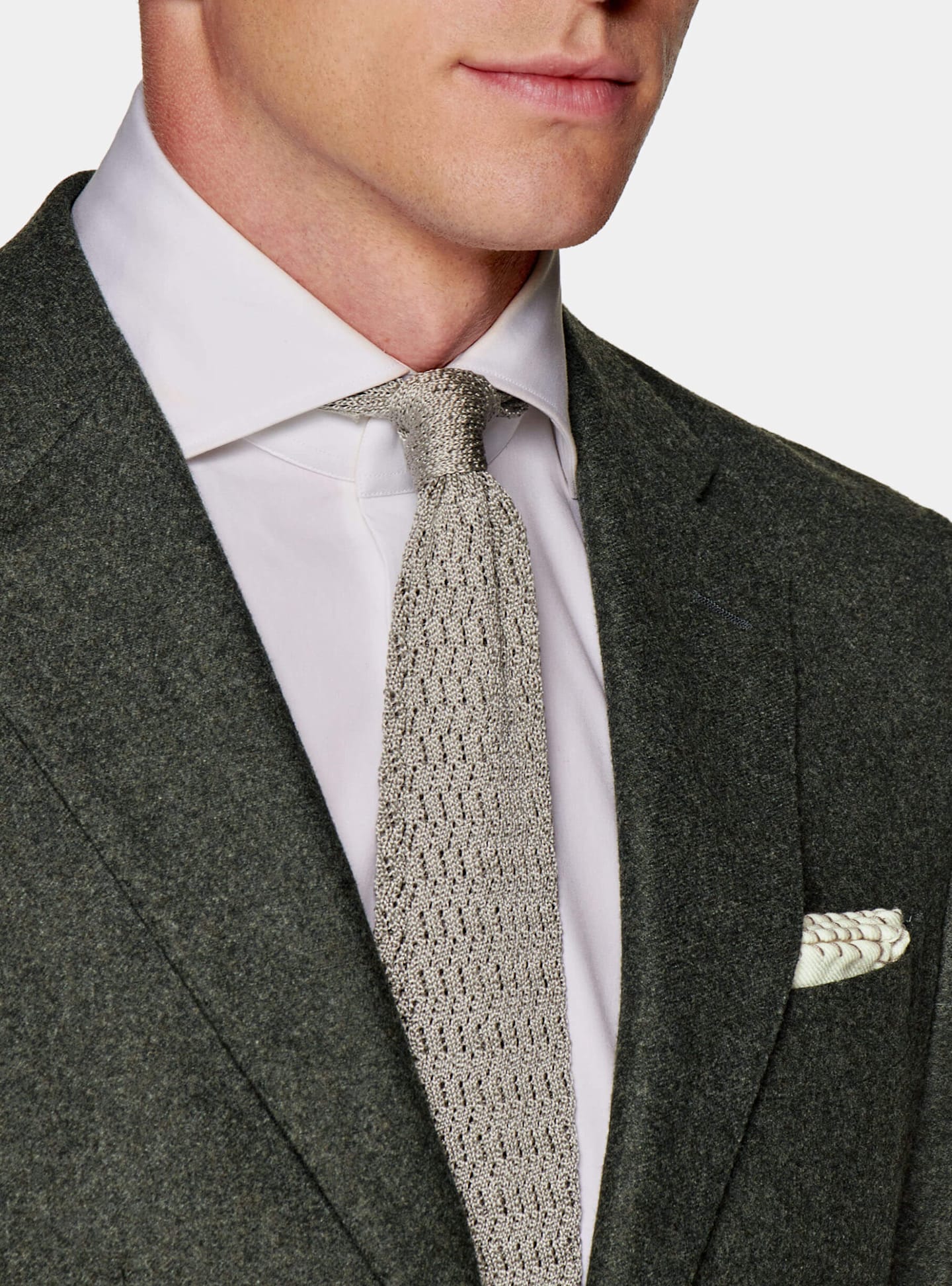 An upclose image on a green circular flannel suit paired with a light brown knitted tie.