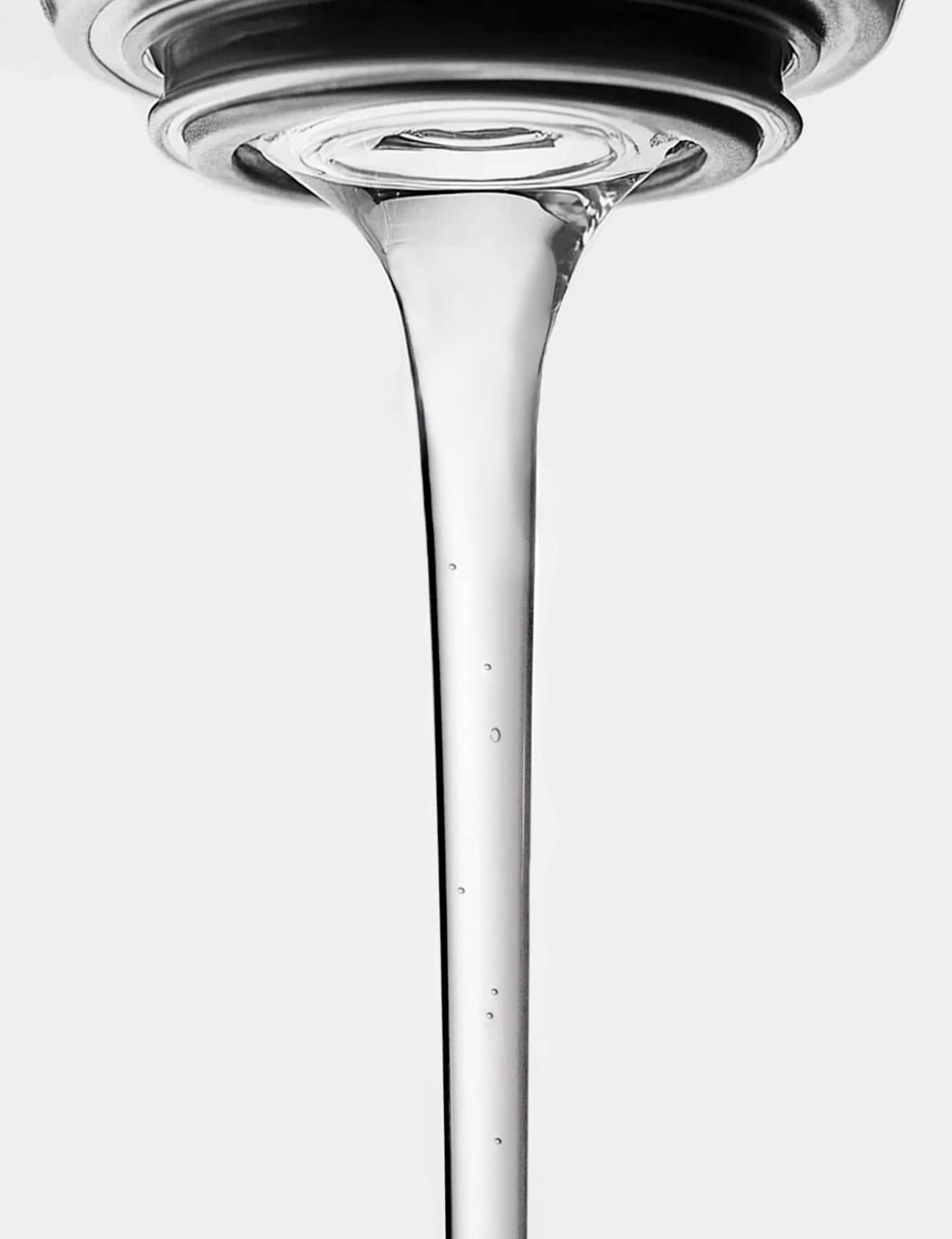 Close-up of clear water flowing from a tap against a white background.