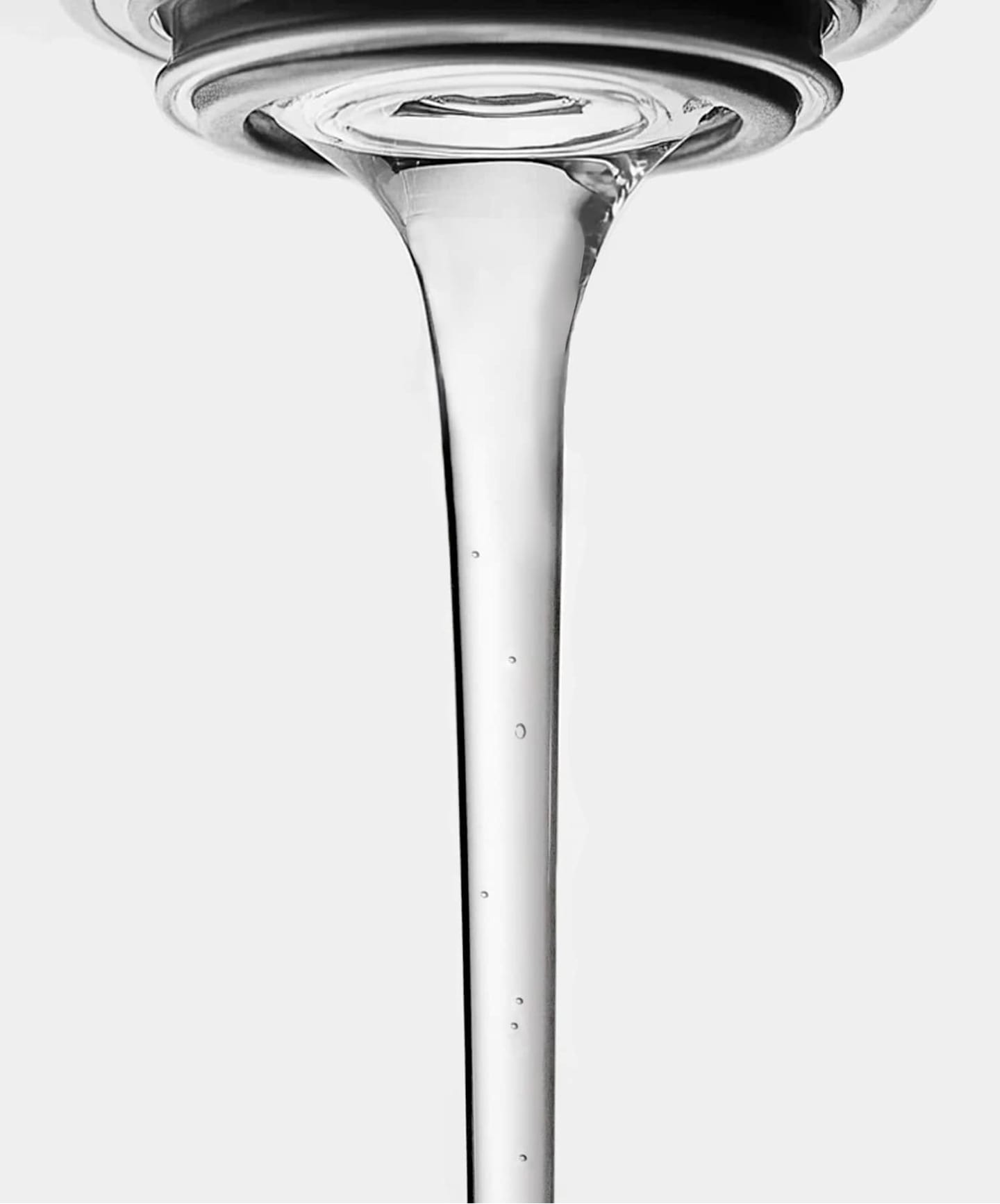 Close-up of clear water flowing from a tap against a white background.