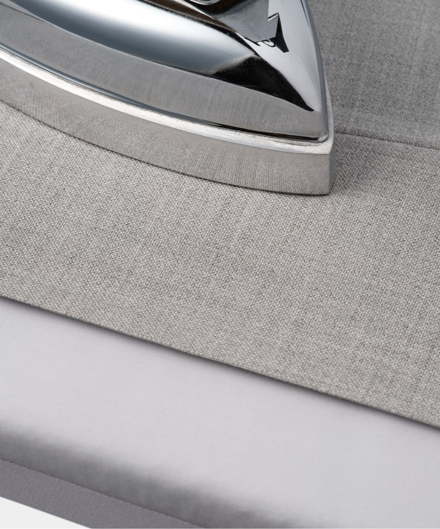 Detailed close-up of an iron placed on a trousers, highlighting its features and texture.