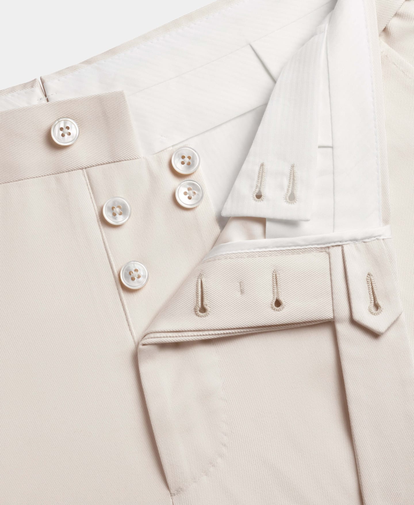 Pantalón marrón claro con bragueta de botones abierta.