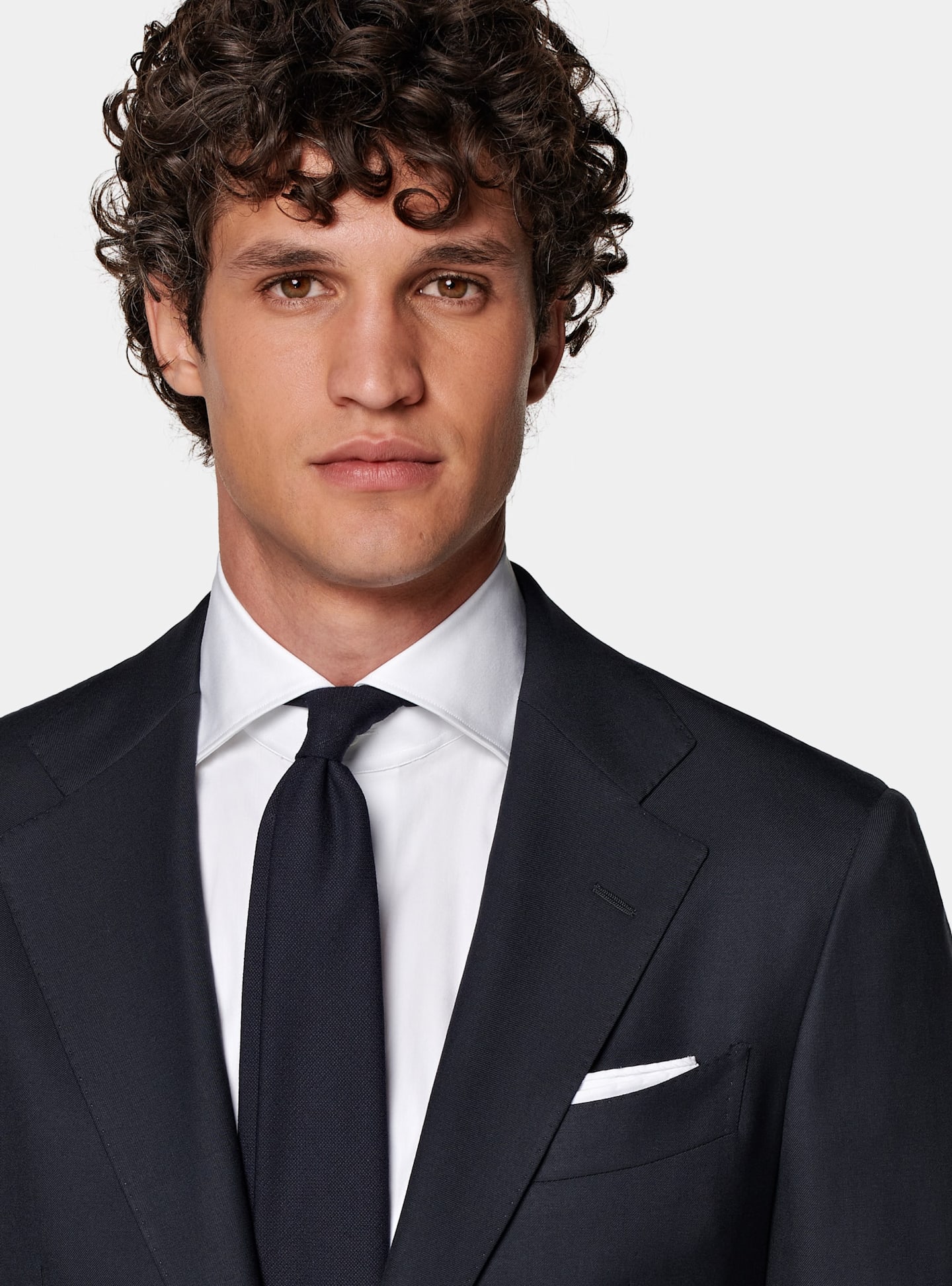 Detail of black two-piece suit with white shirt, black tie, and white pocket square.
