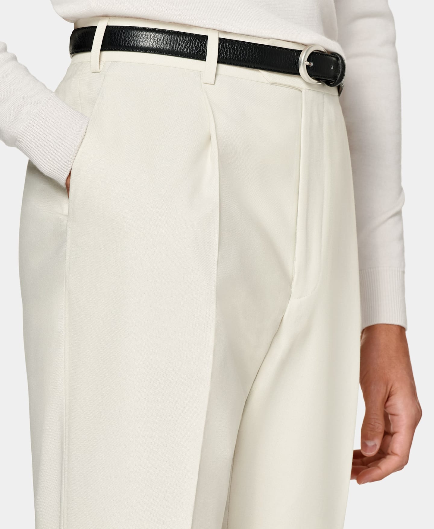 Off-white straight-fit trousers with black belt and white knit.