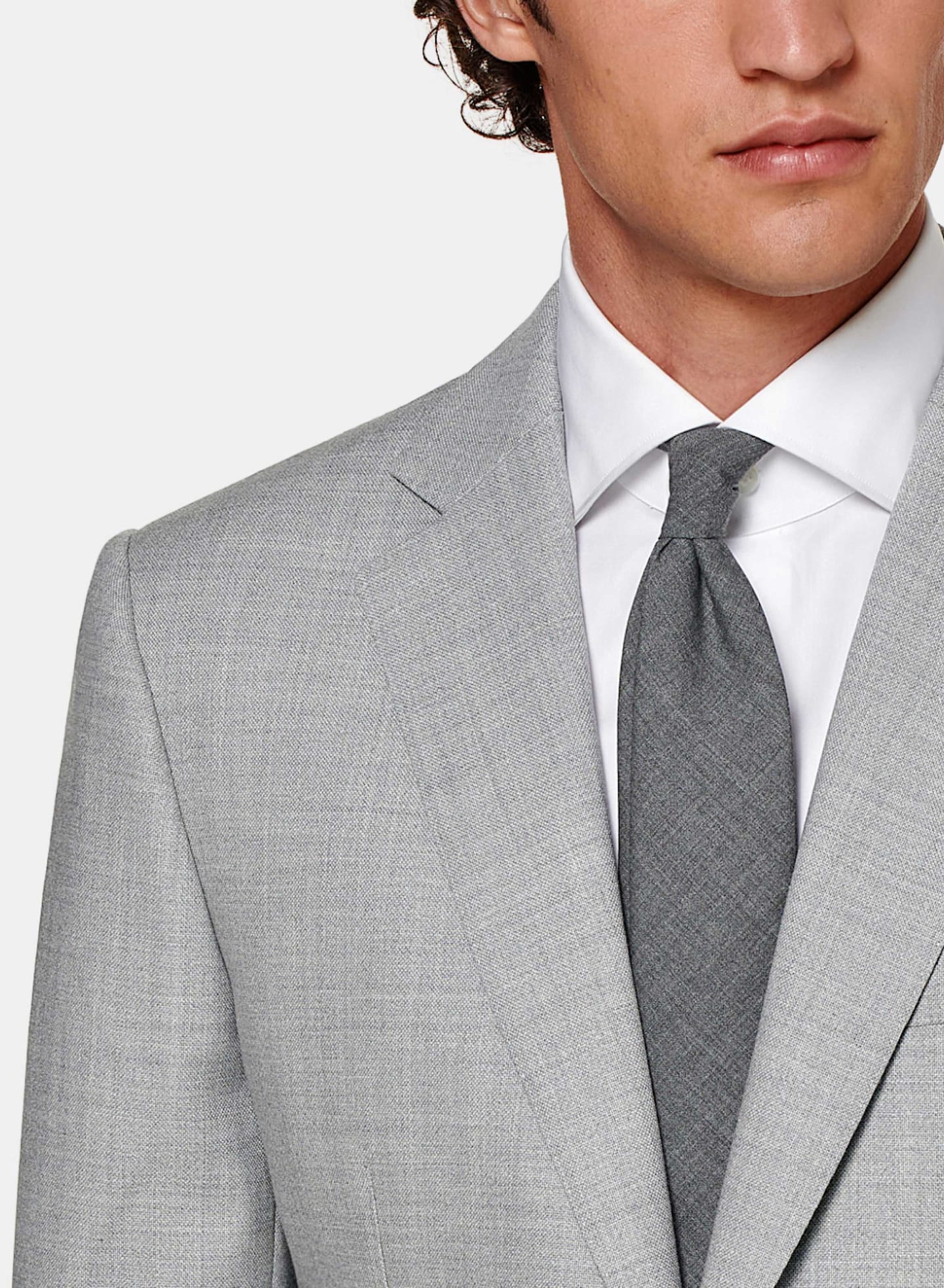 Grey suit with notch lapel, worn with white shirt and grey tie.