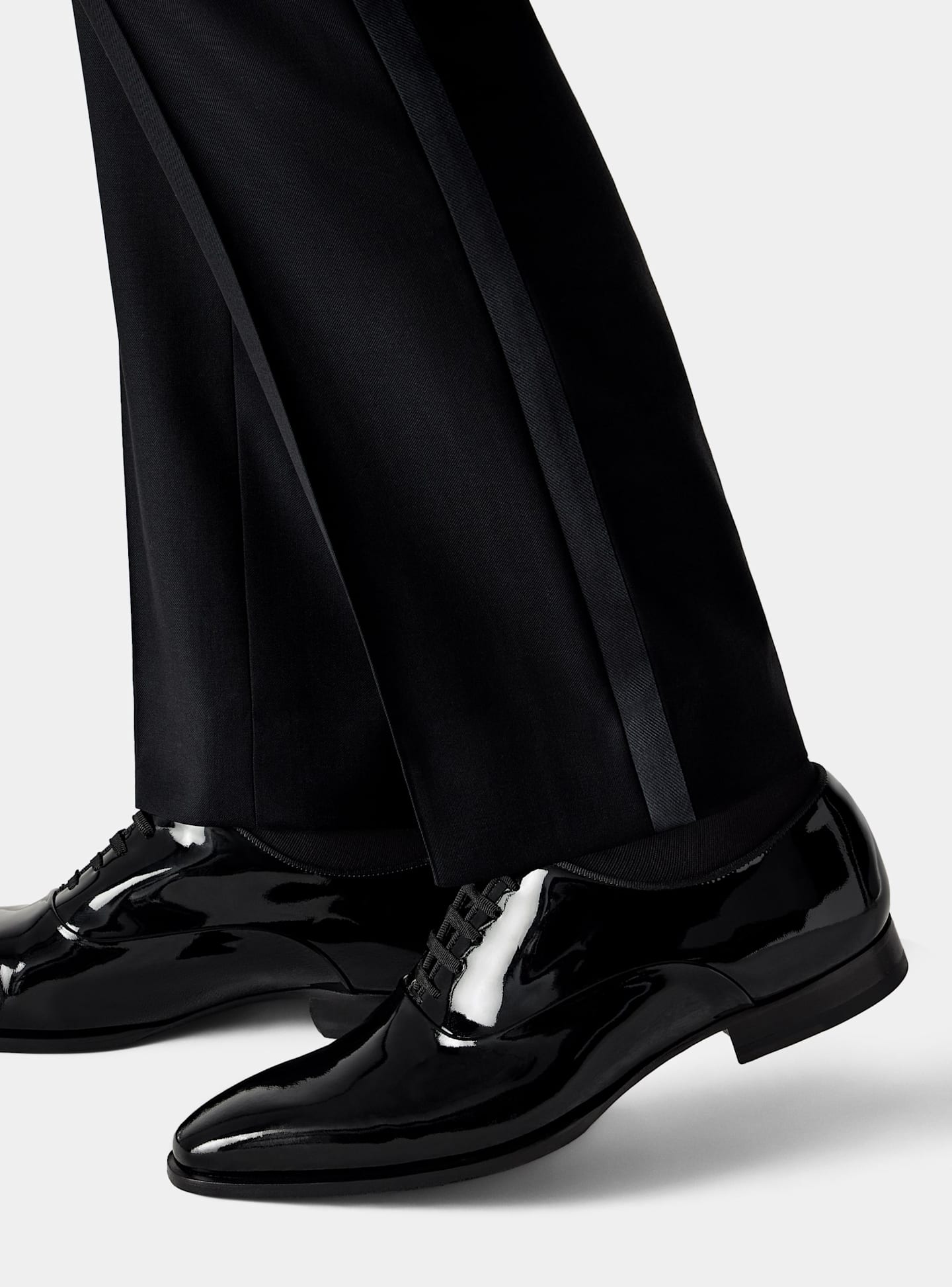 Vue de détail d'un pantalon de smoking noir avec chaussures à lacets en cuir verni noir.