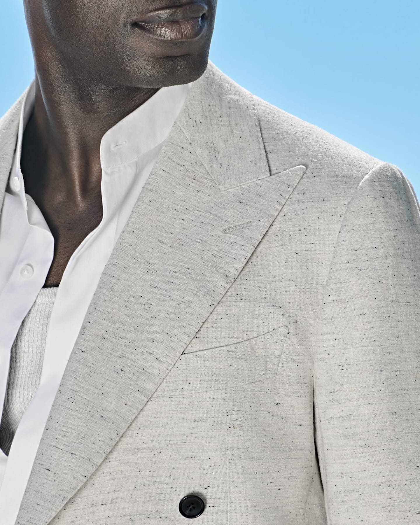 Detail of light blue three-piece suit with white shirt and grey knitted silk tie.