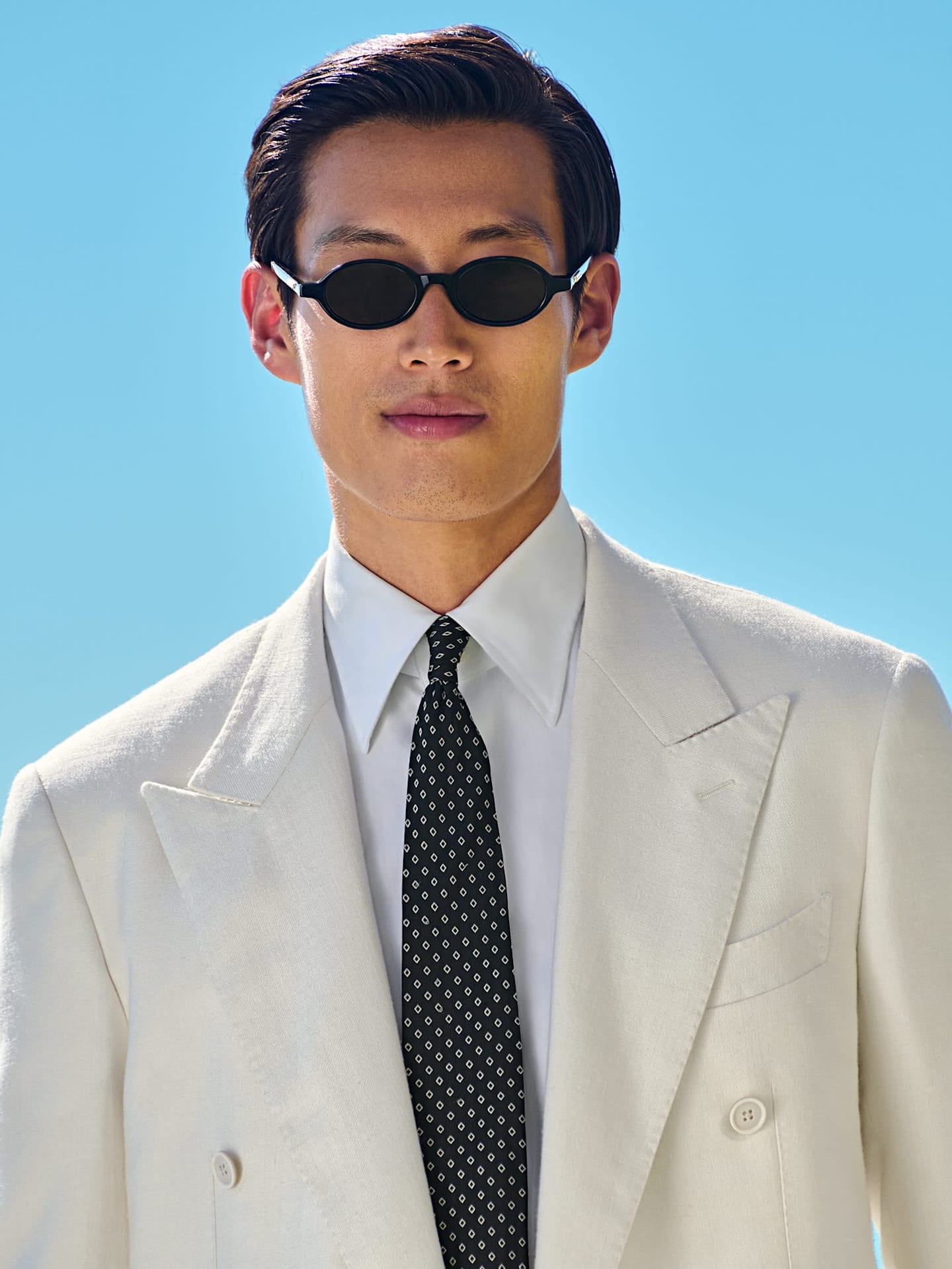 Detail of light blue three-piece suit with white shirt and grey knitted silk tie.