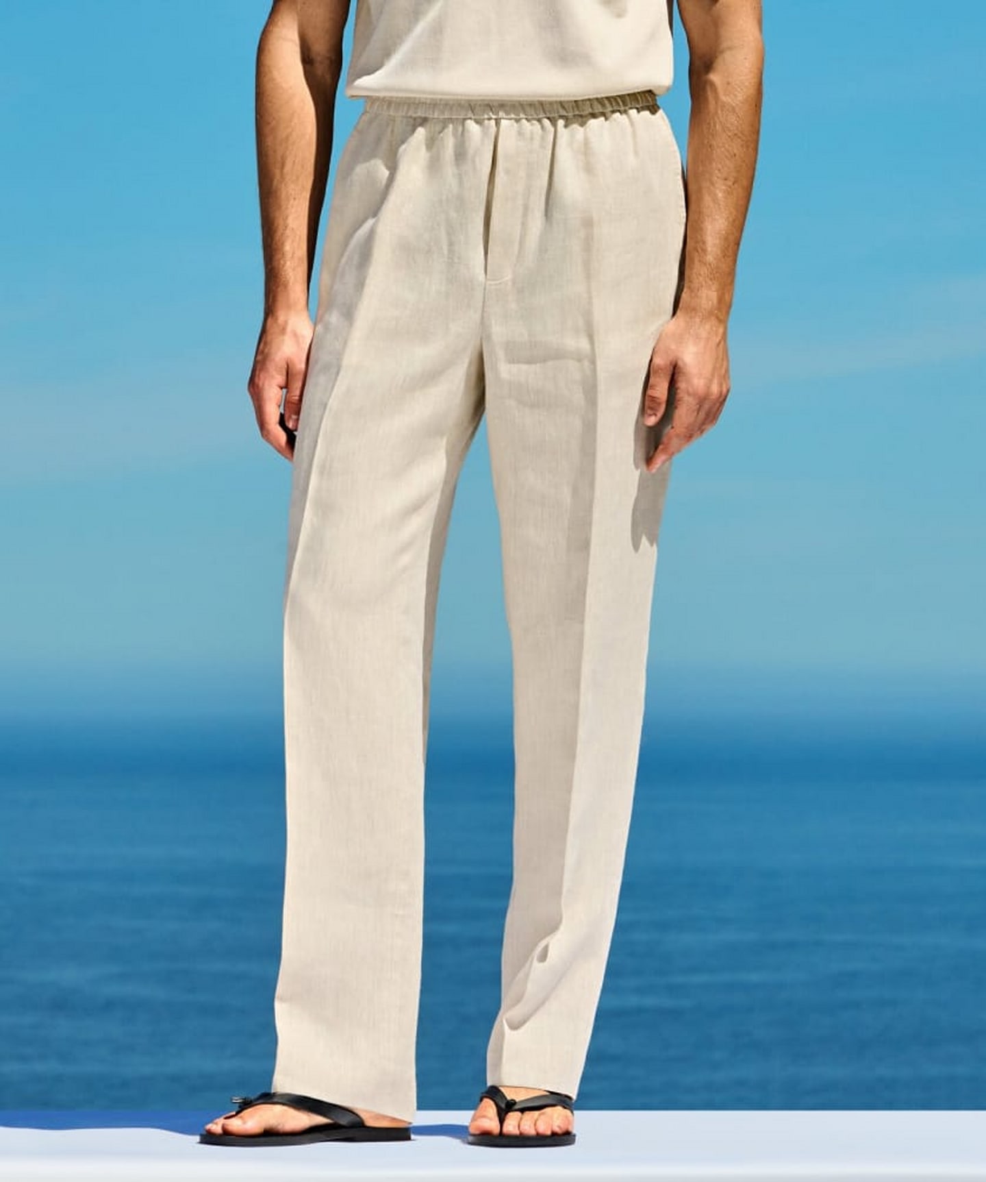 Off-white straight-fit trousers with black belt and white knit.