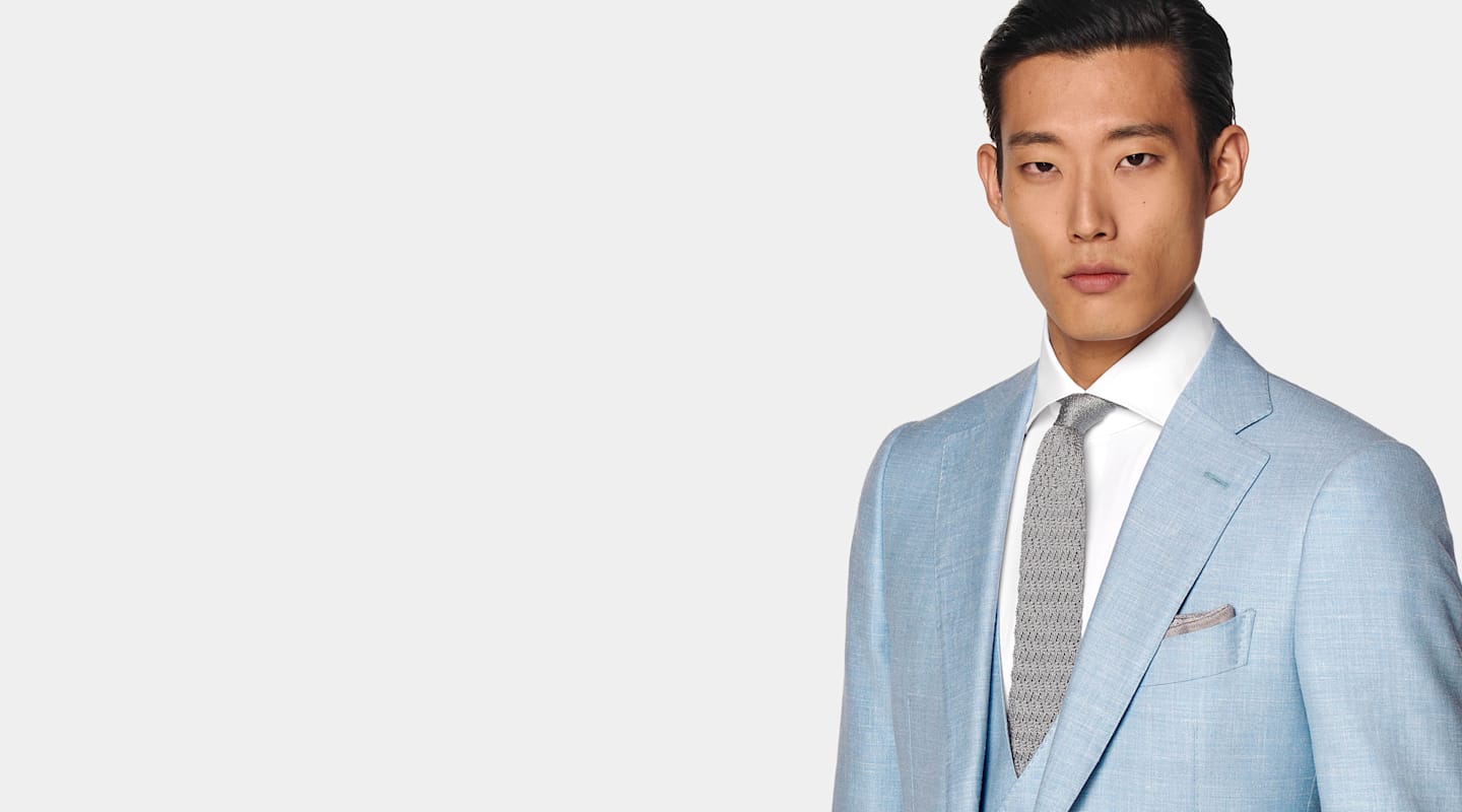 Nahansicht eines hellblauen dreiteiligen Anzugs, kombiniert mit weißem Hemd und grauer Strickkrawatte aus Seide.