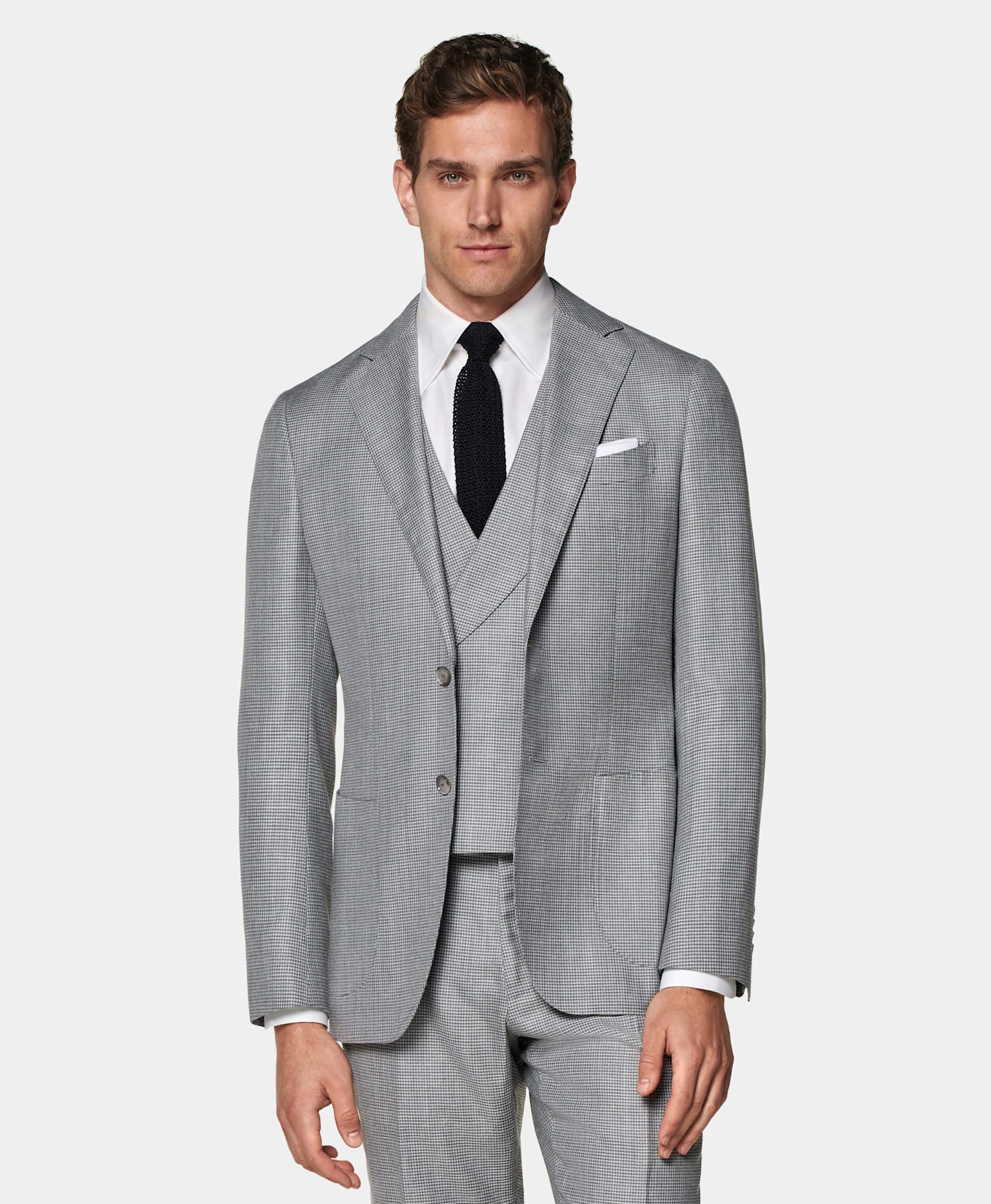 Grey houndstooth check 3-piece suit with white shirt and black knitted silk tie.