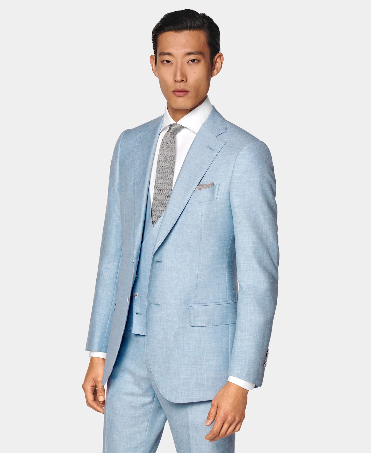 Sommerhochzeit-Outfit für Herren: Hellblauer dreiteiliger Anzug, kombiniert mit weißem Hemd und grauer Strickkrawatte aus Seide.