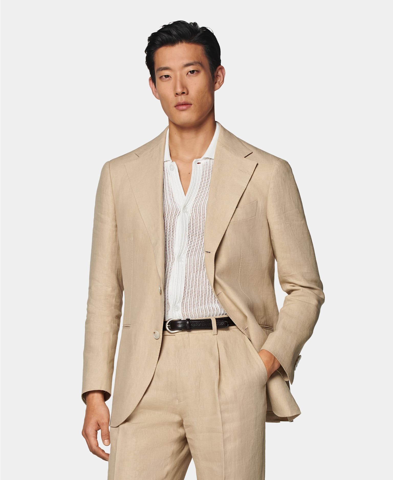 Sand-colored single-breasted suit with off-white crocheted polo shirt and black belt.
