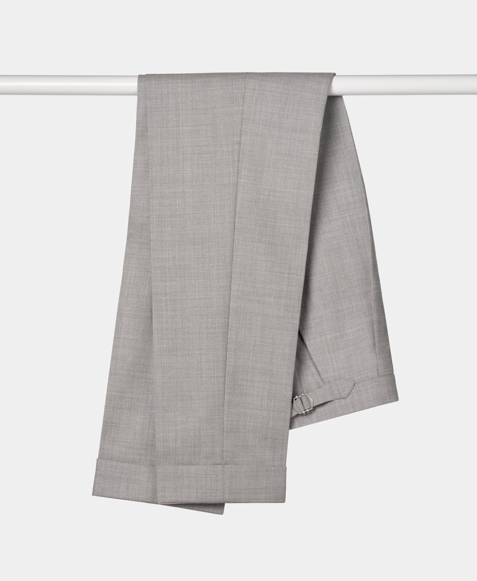A set of grey trousers suspended on a clothes rail, emphasizing their sleek appearance and fabric texture