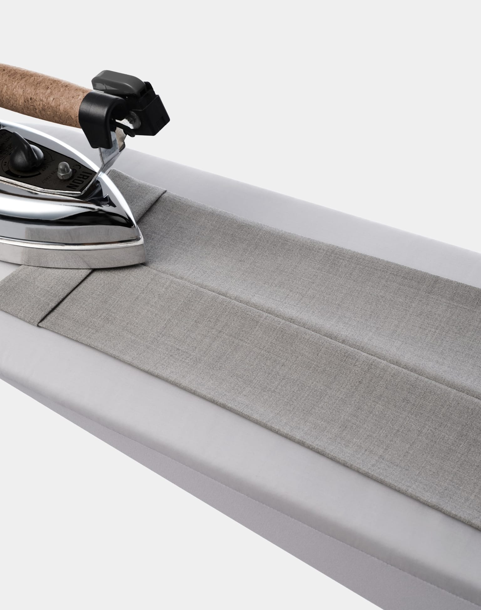  A close-up view of an iron resting on a gray trousers showcasing the texture and details of both items.