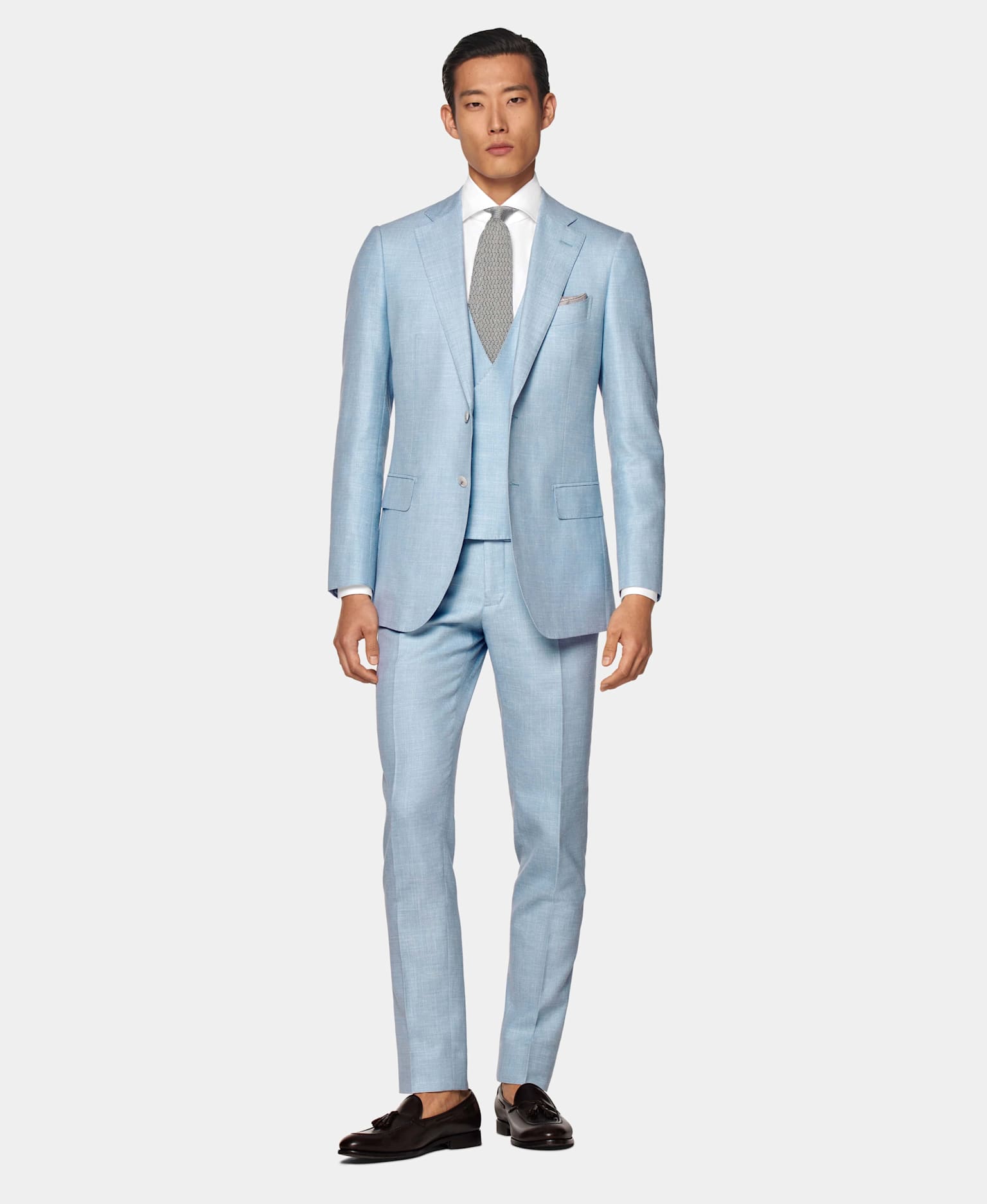 Light blue three-piece suit with white shirt and grey knitted silk tie.