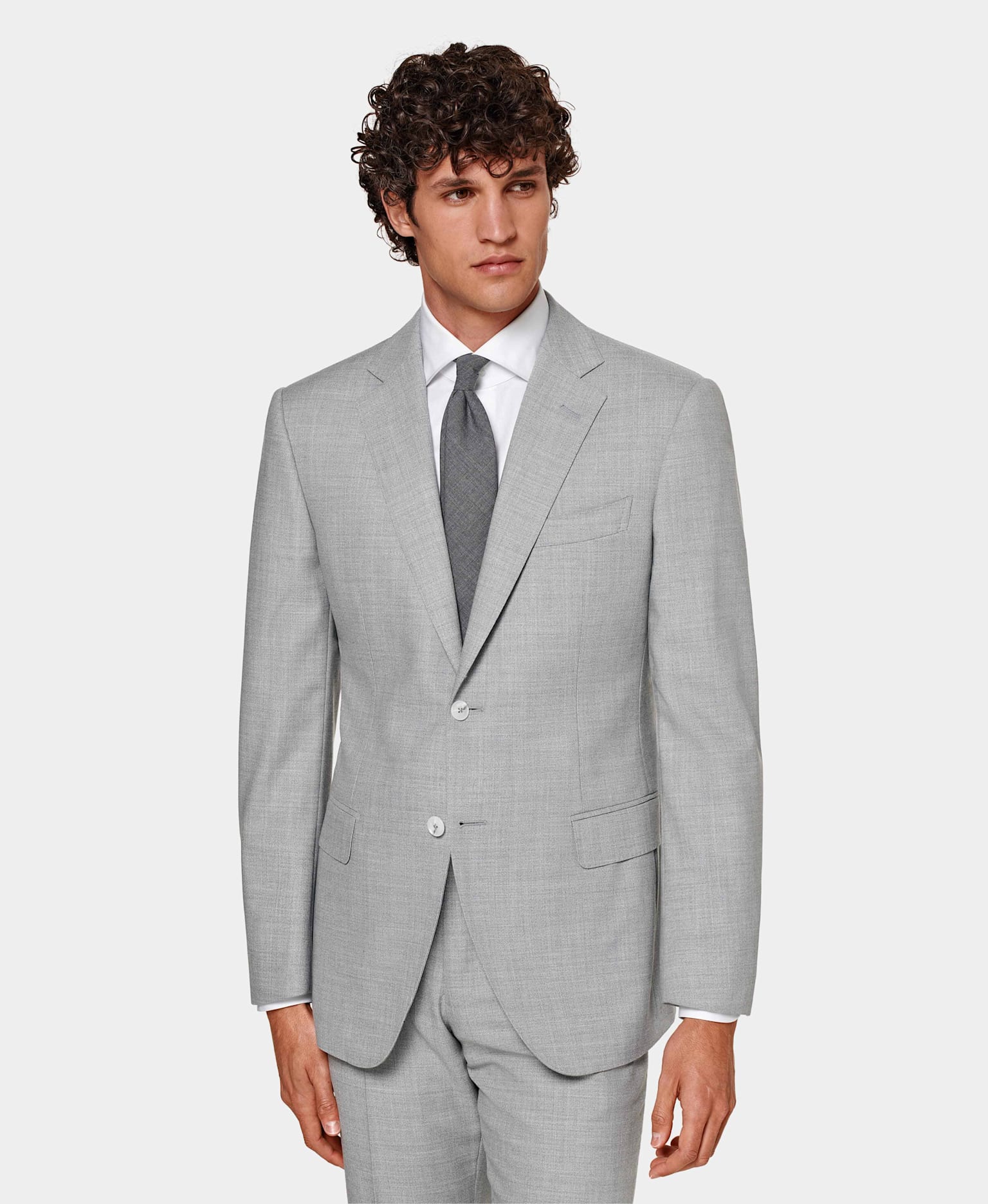Grey suit with flap pockets and notch lapel, worn with white shirt and grey tie.