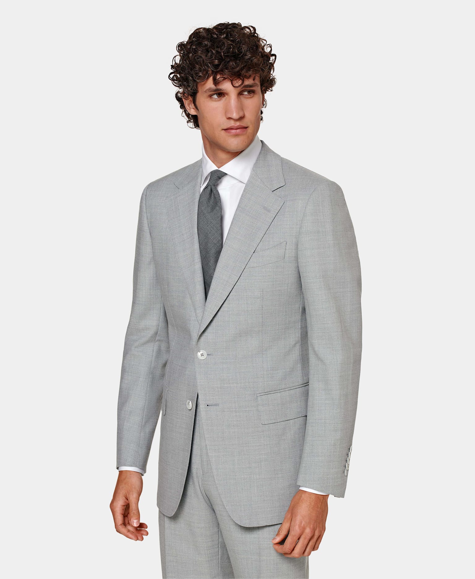 Grey suit with flap pockets and notch lapel, worn with white shirt and grey tie.