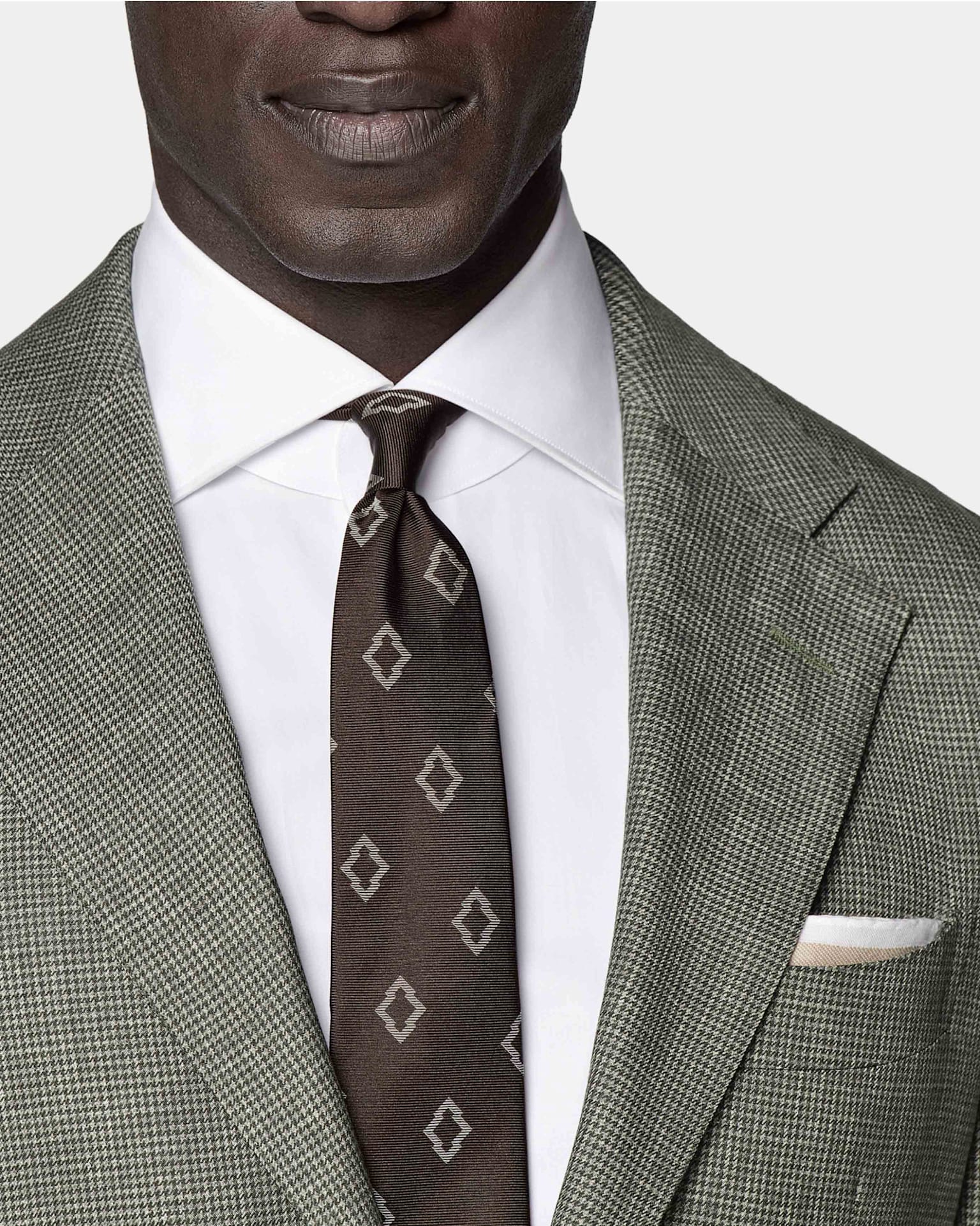 Detail of greey 3-piece houndstooth check suit with white shirt, brown patterned tie tie, and white pocket square.