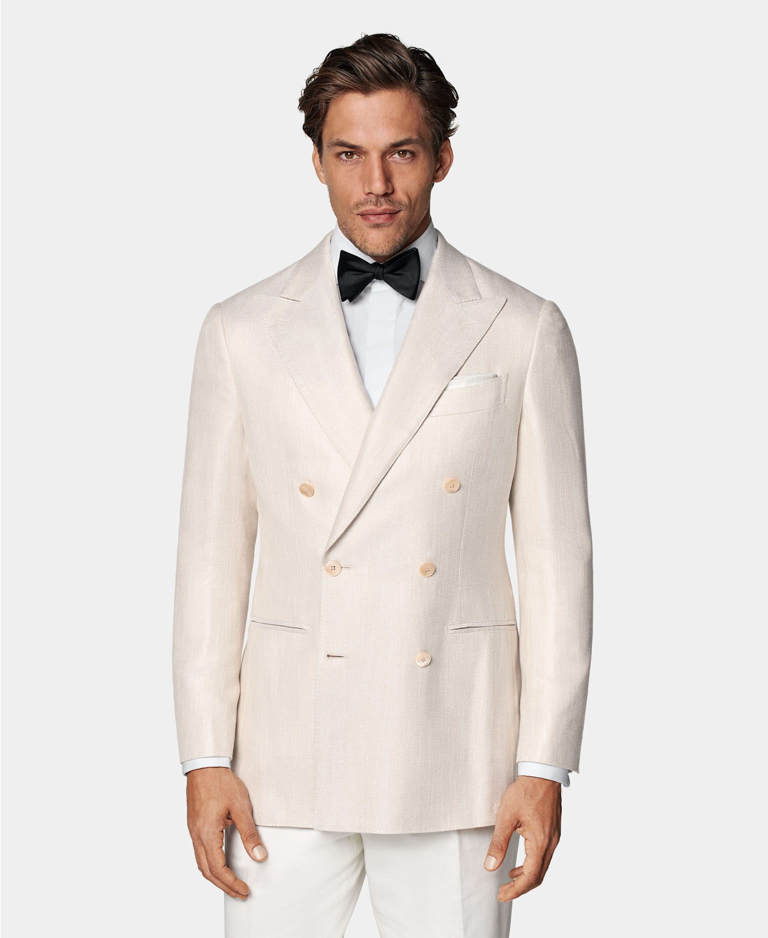 Off-white double-breasted tuxedo with white shirt and black silk bow tie.