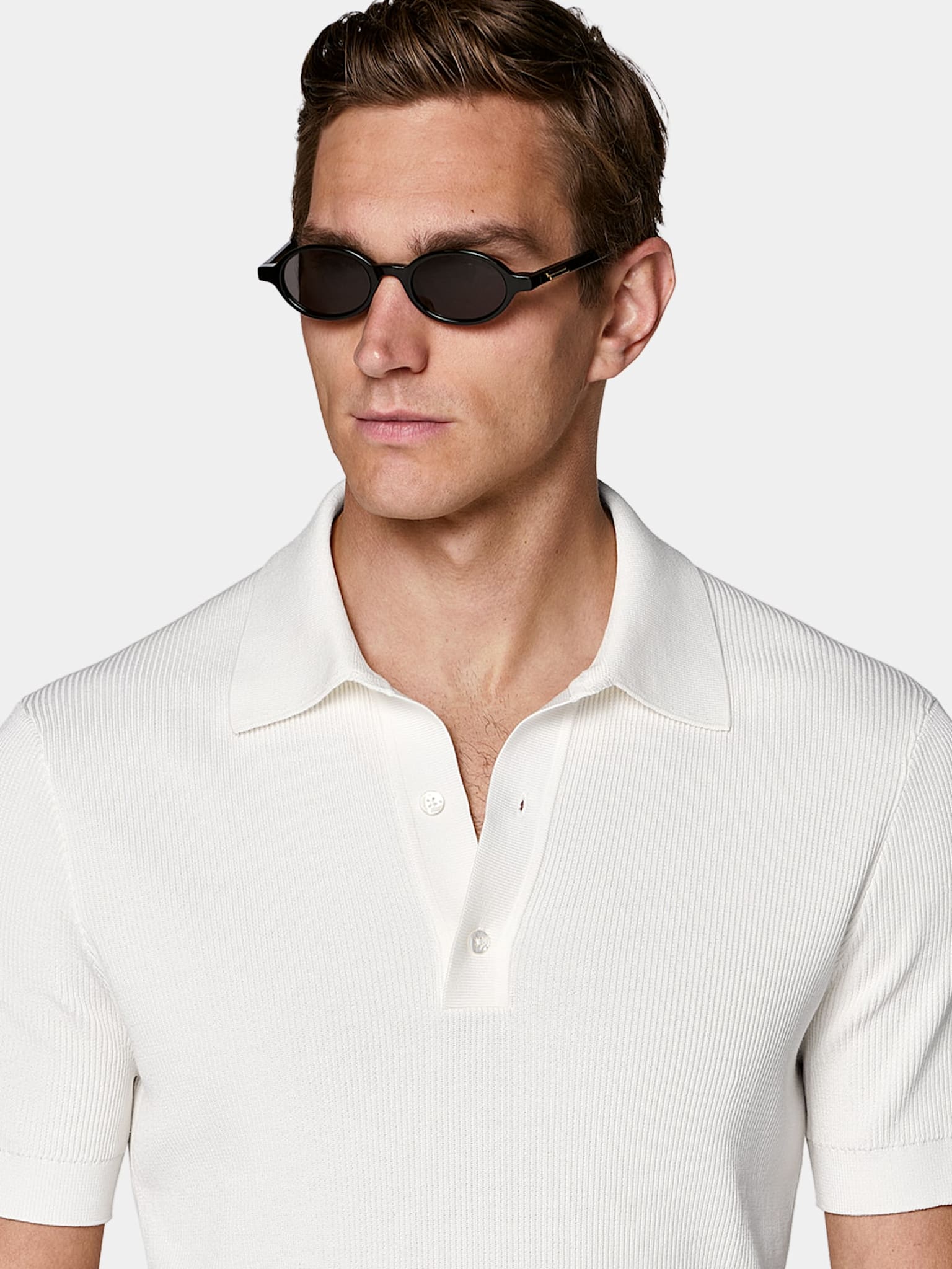 White ribbed polo shirt styled with black sunglasses